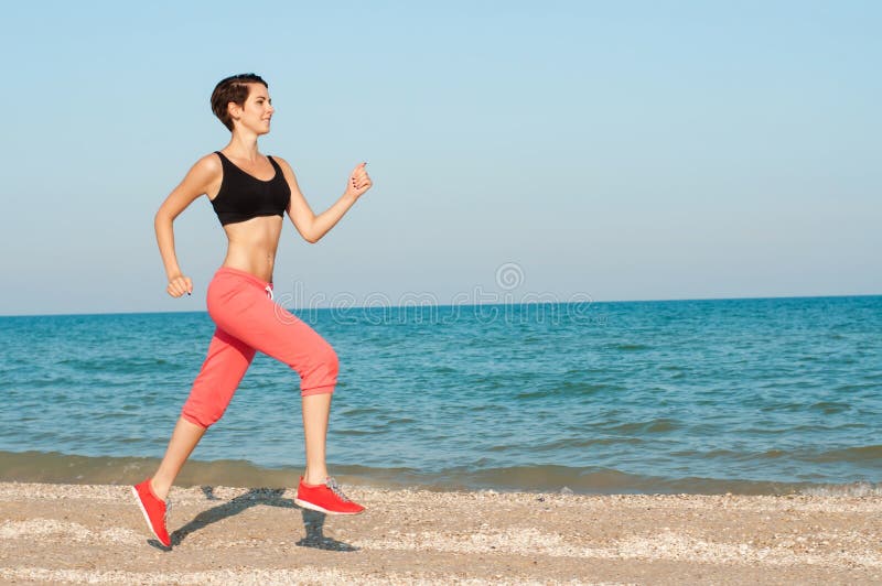 Young beautiful woman athlete running on the beach