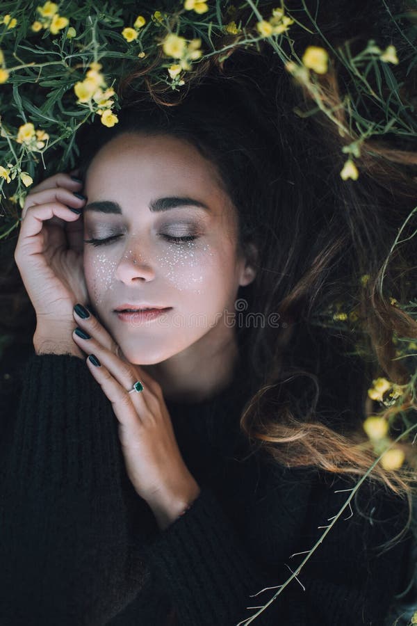 Young beautiful woman with a bright shining make up on a green meadow