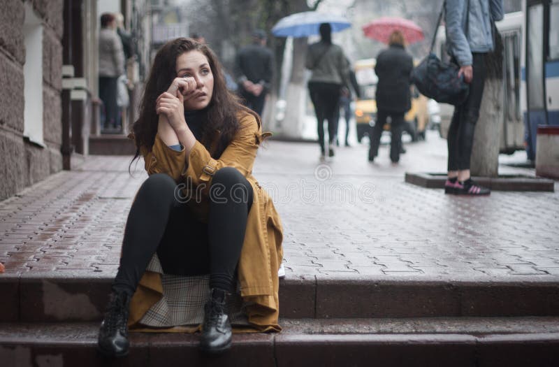 Young beautiful woman cries sitting in the street stock photography Young beautiful woman cries sitting in the street stock photography