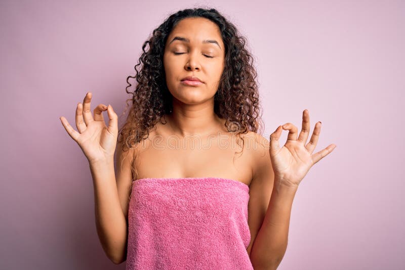 Young beautiful woman with curly hair wearing shower towel after bath over pink background relax and smiling with eyes closed