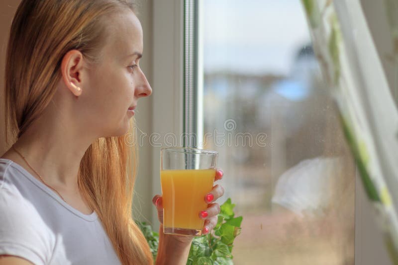 Young beautiful woman drinking juice near window royalty free stock images
