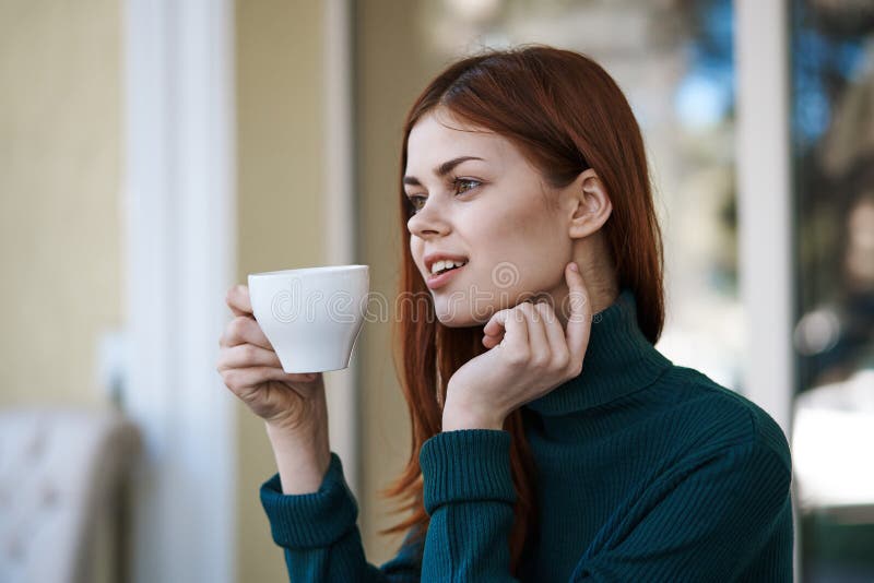 Young beautiful woman drinks coffee in a cafe