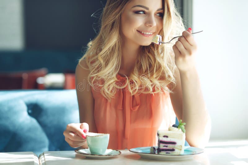 Young beautiful woman eating dessert. Cheerful attractive young woman with long hair and eating dessert.