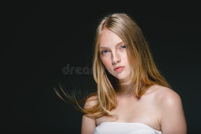 Young beautiful woman face portrait with healthy skin over dark