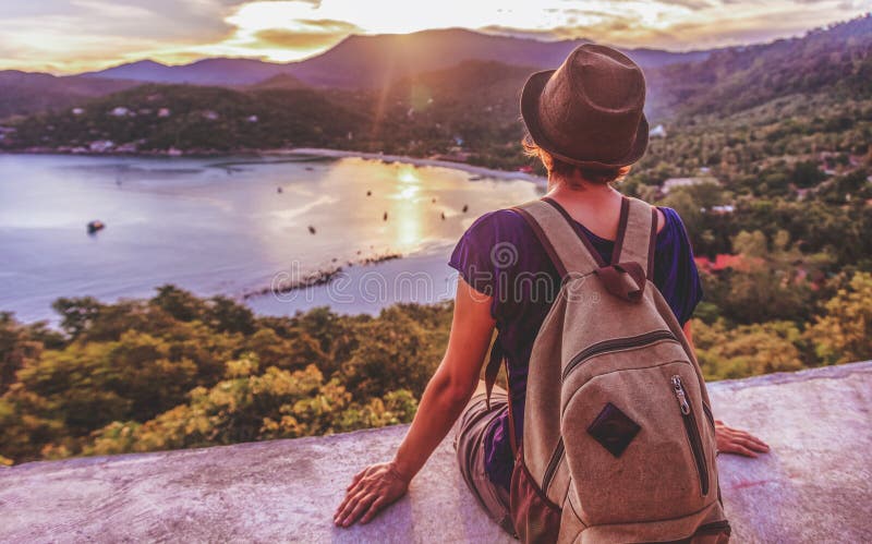 Young beautiful woman hipster traveler looking at sunset and beautiful seascape with a lookout point. Freedom, travel, vacation stock images Young beautiful woman hipster traveler looking at sunset and beautiful seascape with a lookout point. Freedom, travel, vacation stock images
