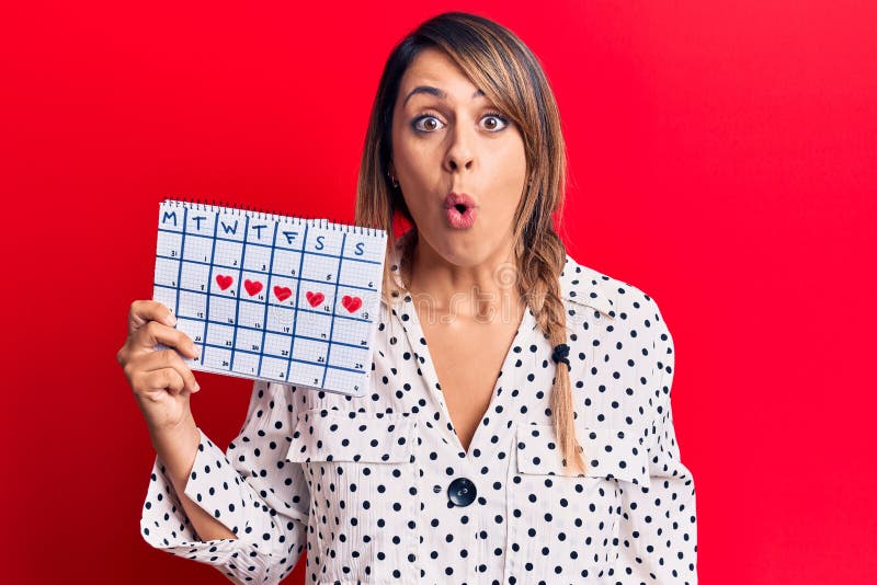 Young Beautiful Woman Holding Period Calendar Scared And Amazed With