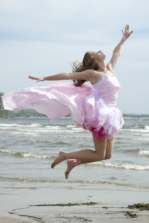 Young beautiful woman jumping on the beach.