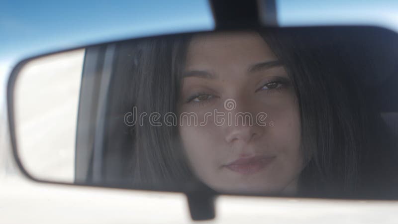 Close up Young beautiful woman looking in rear view mirror while sitting in car