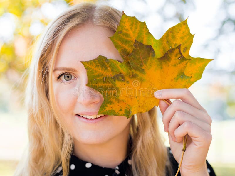 Young and beautiful woman in nature holding amazing color leave