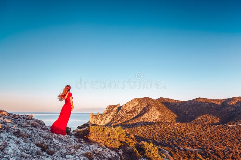 Young beautiful woman in red dress looking to mountains sea stock images Young beautiful woman in red dress looking to mountains sea stock images
