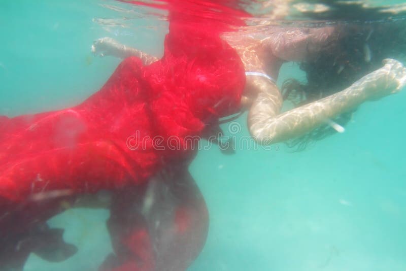 Young beautiful woman in red dress underwater