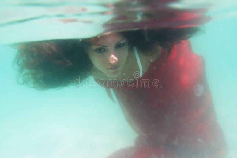 Young beautiful woman in red dress underwater