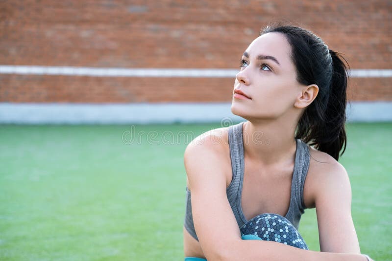 Young beautiful woman resting after the jogging in the city. fitness girl sitting on floor and relaxing after workout