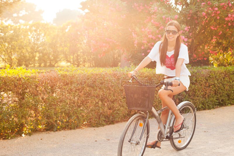 Young beautiful woman riding bicicle on summer