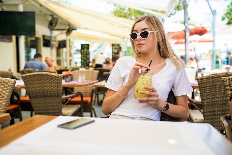 Young beautiful woman in round sunglasses with cocktail at the terrace of cafe having fun stock photos Young beautiful woman in round sunglasses with cocktail at the terrace of cafe having fun stock photos