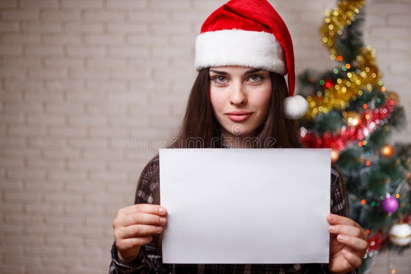 Young beautiful woman in Santa cap with empty board in hands. Fr