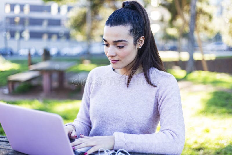Young beautiful woman sitting outdoors while working with computer royalty free stock photography