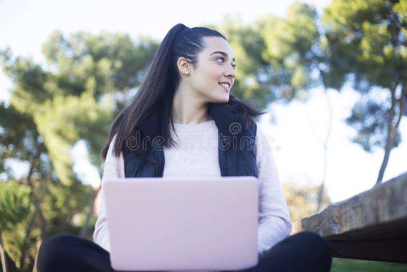 Young beautiful woman sitting outdoors while working with computer stock images