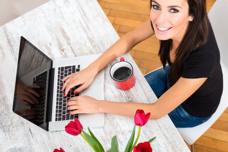 Young beautiful woman smiling while using a Laptop at home