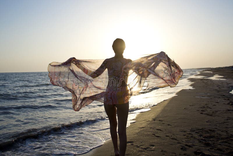 Young beautiful woman in swimsuit standing on the beach. stock photo Young beautiful woman in swimsuit standing on the beach. stock photo