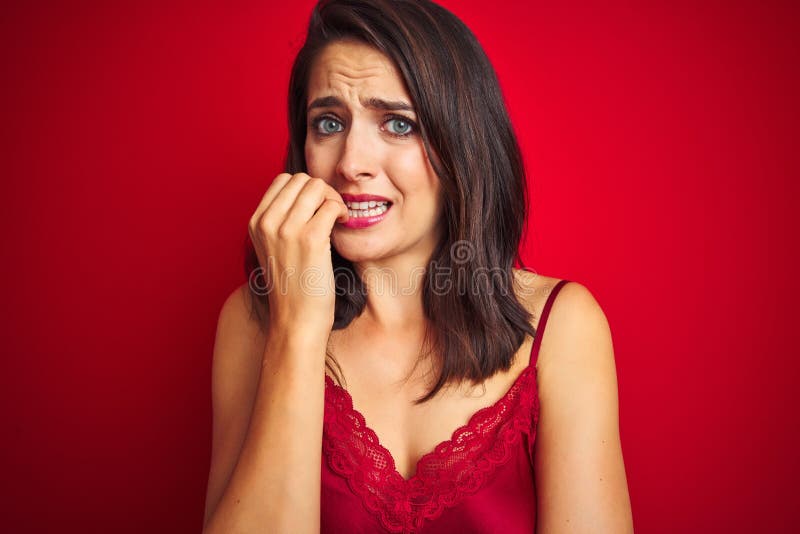 Young beautiful woman wearing sexy lingerie over red isolated background looking stressed and nervous with hands on mouth biting