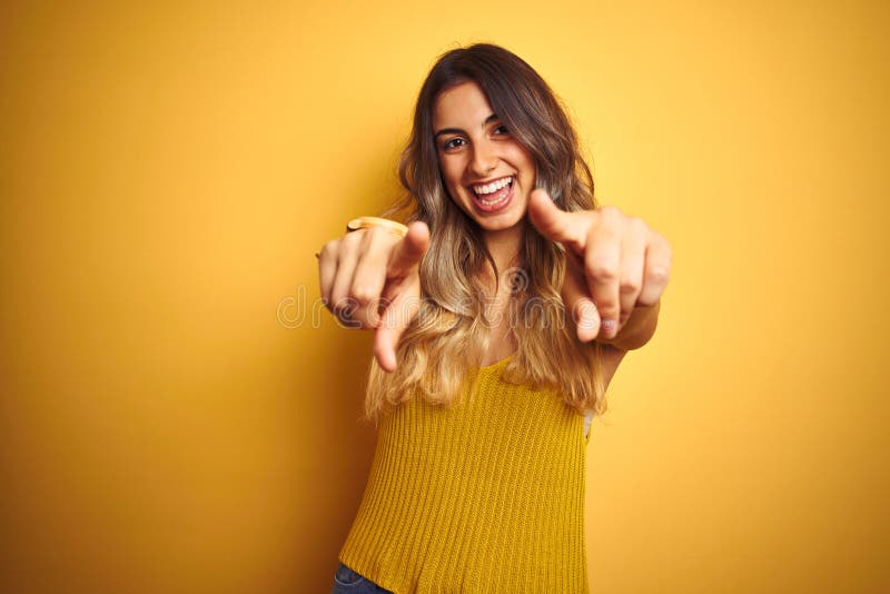 Young beautiful woman wearing t-shirt over yellow isolated background pointing to you and the camera with fingers, smiling