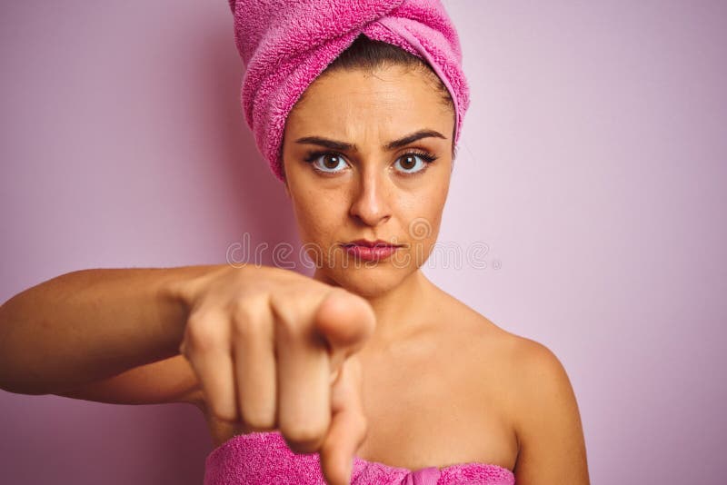 Young beautiful woman wearing towel after shower over isolated pink background pointing with finger to the camera and to you, hand