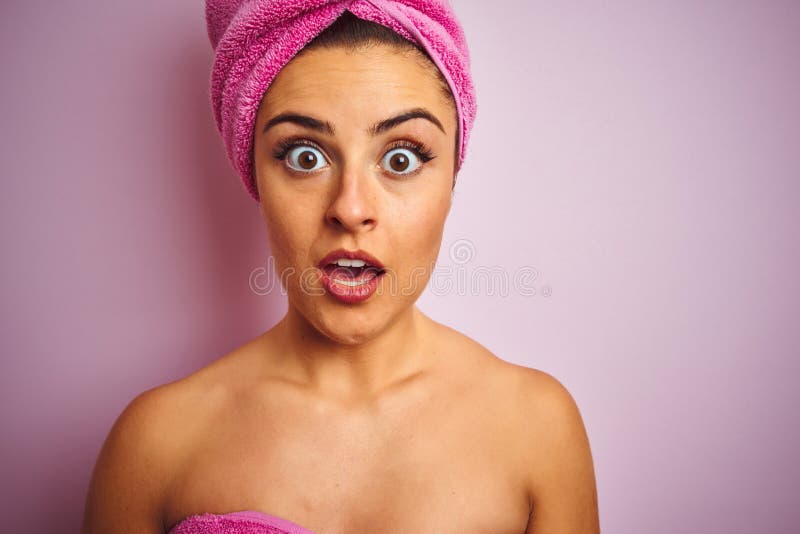 Young beautiful woman wearing towel after shower over isolated pink background scared in shock with a surprise face, afraid and