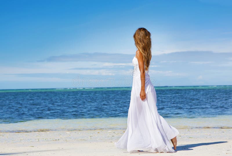 Young beautiful woman in wedding dress on tropical beach stock photo Young beautiful woman in wedding dress on tropical beach stock photo