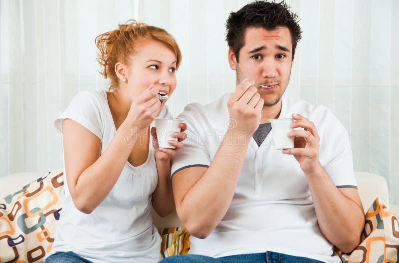 Young, beauty girl and boy eating yoghurt