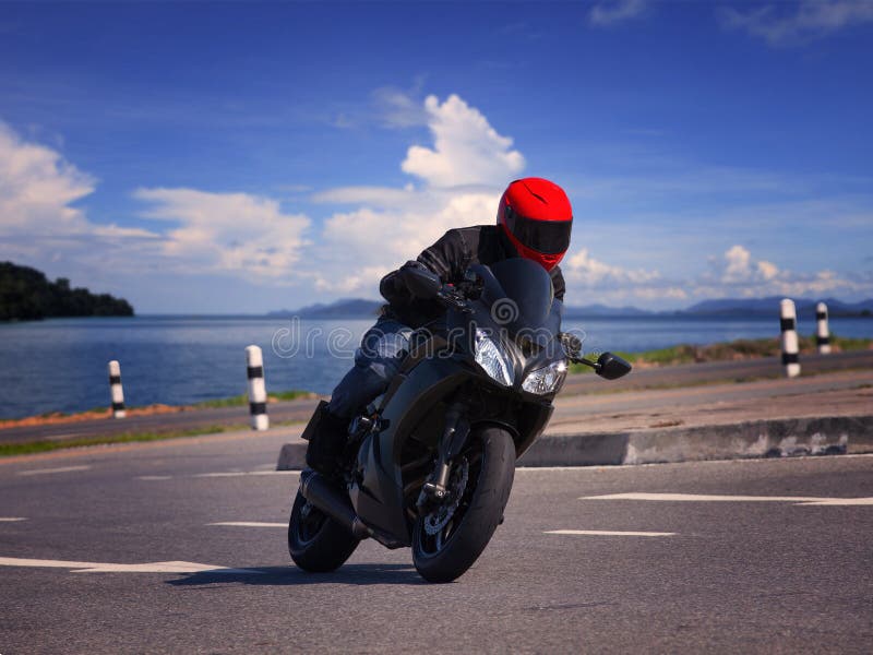 young biker man riding motorcycle on asphalt road against beautiful sea water background stock photography young biker man riding motorcycle on asphalt road against beautiful sea water background stock photography