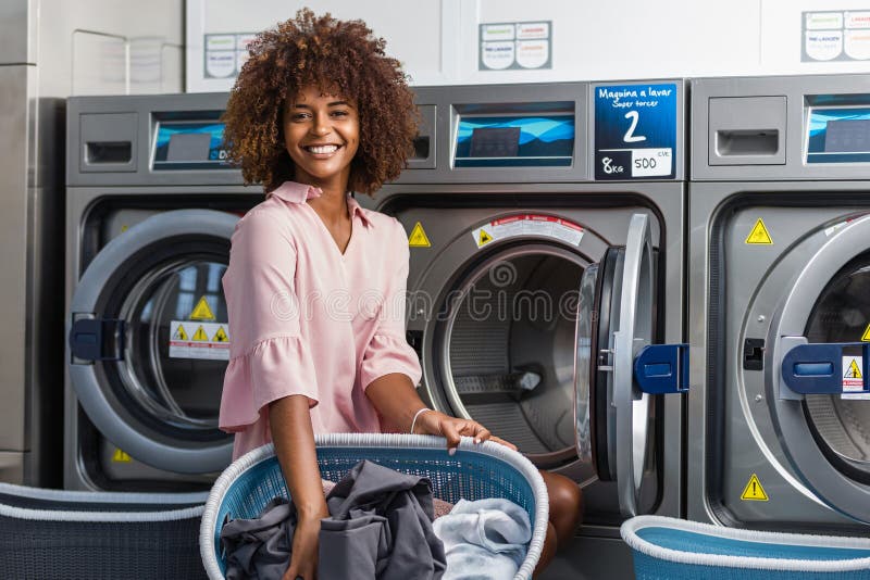 Young black African American woman washing her clothes in a automatic laundry