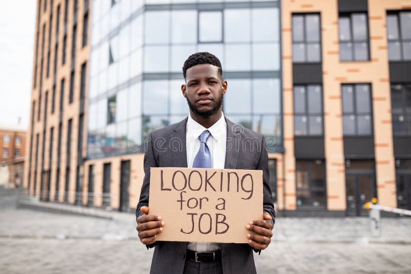 Young Black Businessman Holding Cardboard Sign With The Text Looking