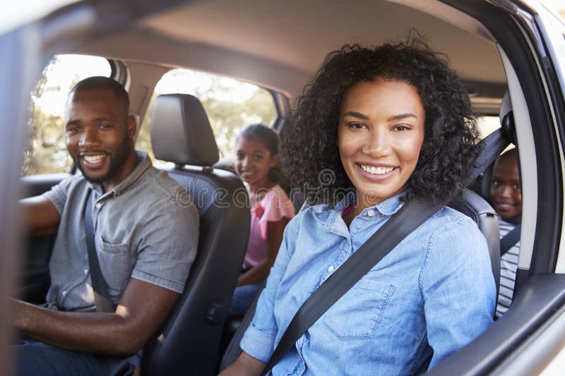 Young black family in a car on a road trip smiling to camera