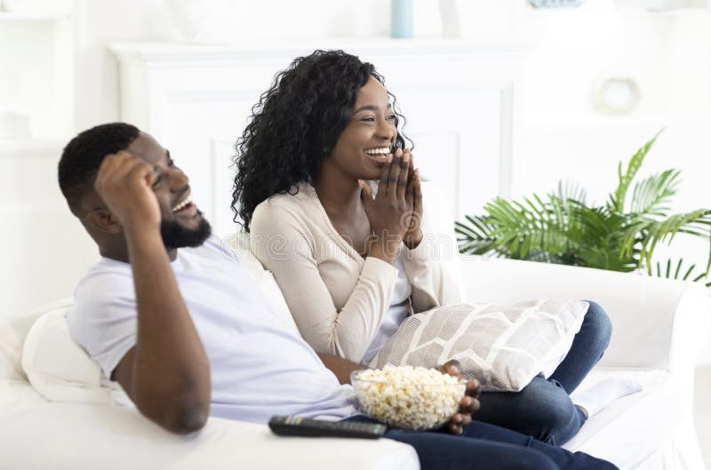 Young black family couple watching comedy movie on tv