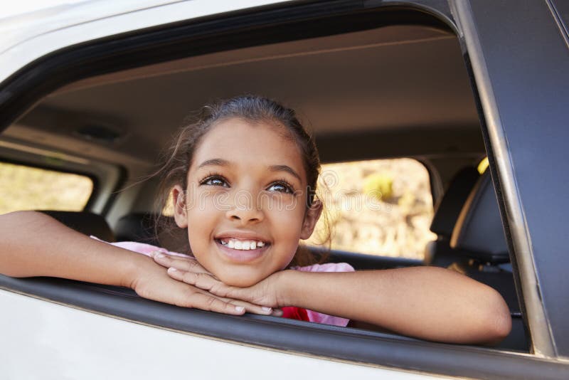 Young black girl looking up out of car window smiling