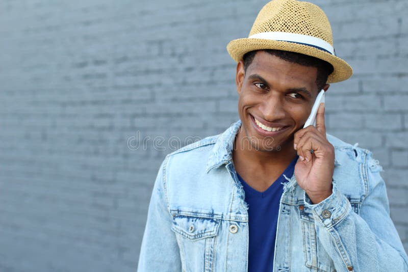 Young black man smiling and talking on mobile phone outside with copy space on the left royalty free stock photo Young black man smiling and talking on mobile phone outside with copy space on the left royalty free stock photo