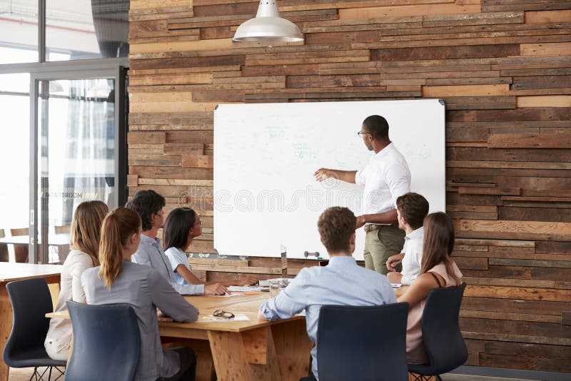 Young black man at whiteboard giving a business presentation stock photography