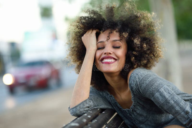 Young black woman with afro hairstyle smiling in urban background stock photo Young black woman with afro hairstyle smiling in urban background stock photo