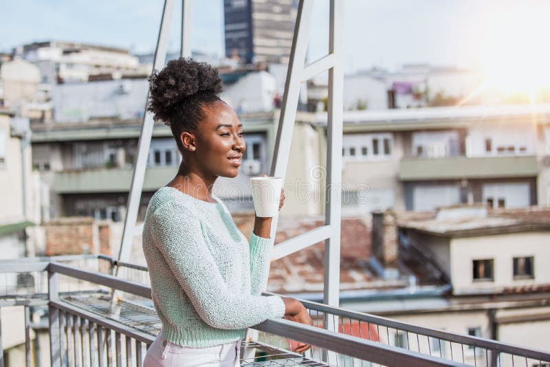 A Young Black Woman is Having Coffee on the Balcony. African American ...