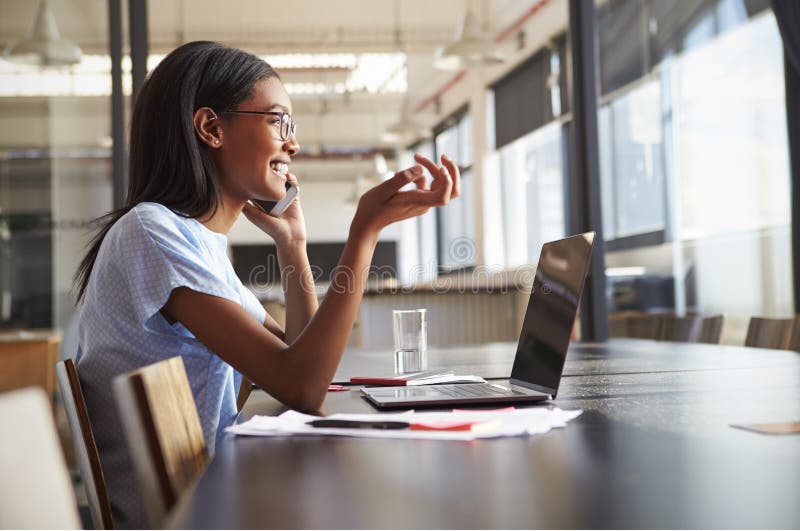 Young black woman in office talking on smartphone