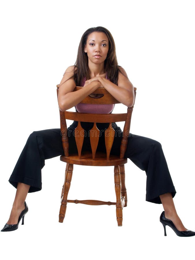 Young black woman in pants outfit sitting on chair backwards royalty free s...