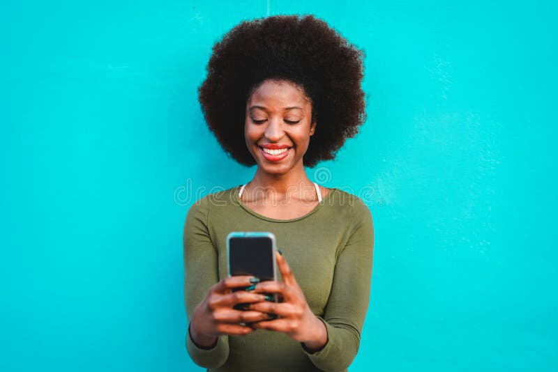 Young black woman using smart mobile phone - African girl laughing and smiling using web app on cellphone - Female lifestyle and