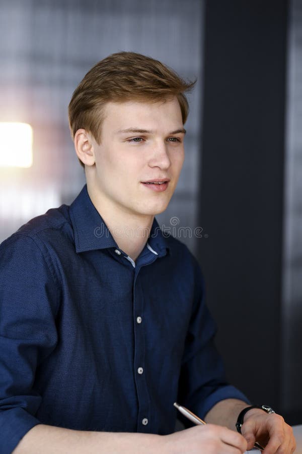 Young blond businessman working with computer in in a darkened office, glare of light on the background royalty free stock photo
