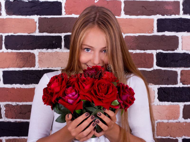 Young blond girl smelling the roses and looking at the camera stock image Young blond girl smelling the roses and looking at the camera stock image