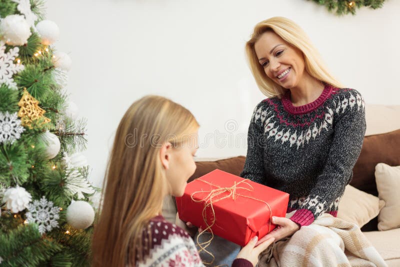 Young blond haired woman giving Christmas gift to her teenage daughter stock photos Young blond haired woman giving Christmas gift to her teenage daughter stock photos