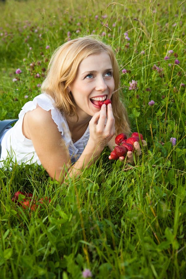 Young blond woman eating strawberries