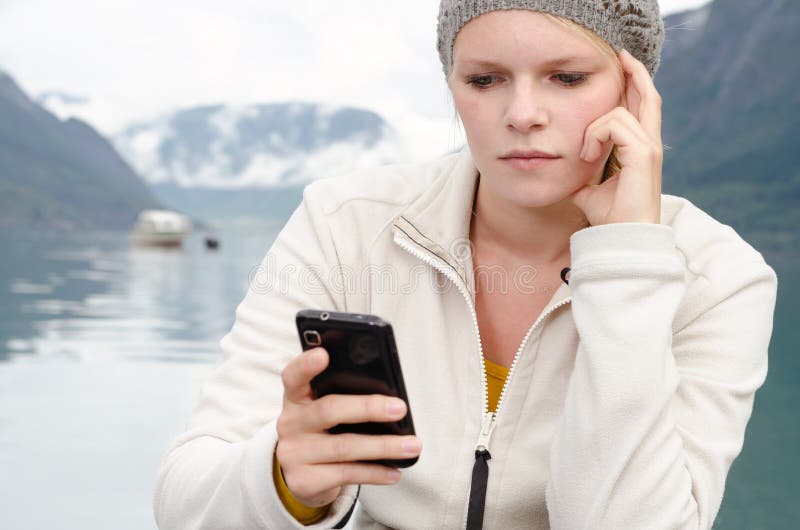 Young blond woman with her Smartphone in the hand