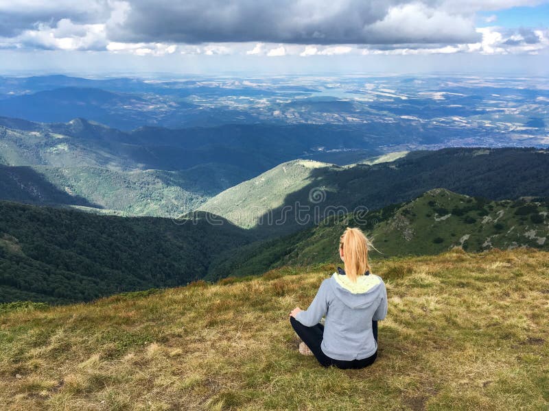 Young blond woman sitting meditating a mountain view stock photo Young blond woman sitting meditating a mountain view stock photo