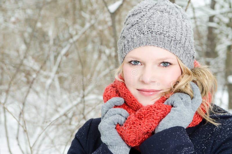 Young blond woman with beanie and scarf winter wood portrait